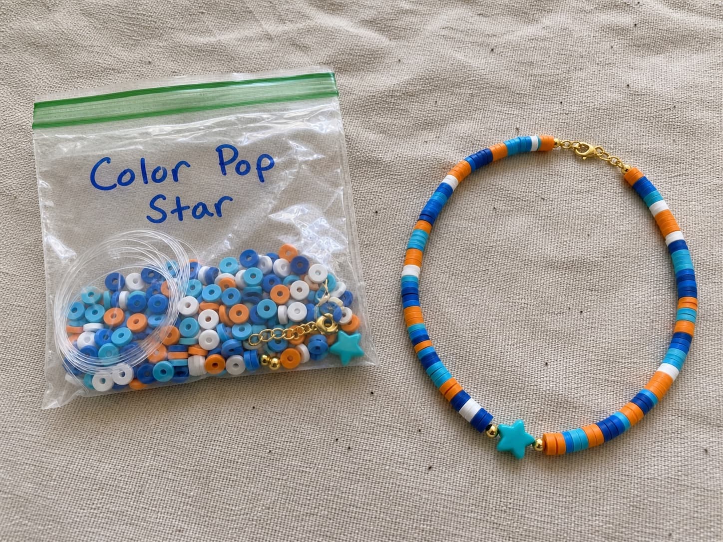 Handmade blue and orange Color Pop Star necklace beside its clear DIY bead kit
