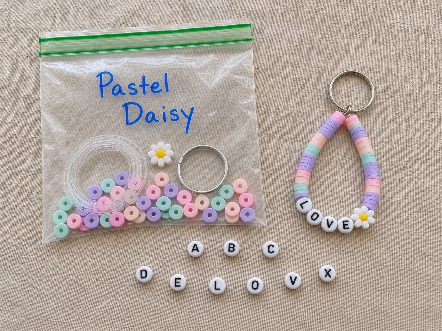 Finished pastel LOVE keychain beside its clear DIY bead kit