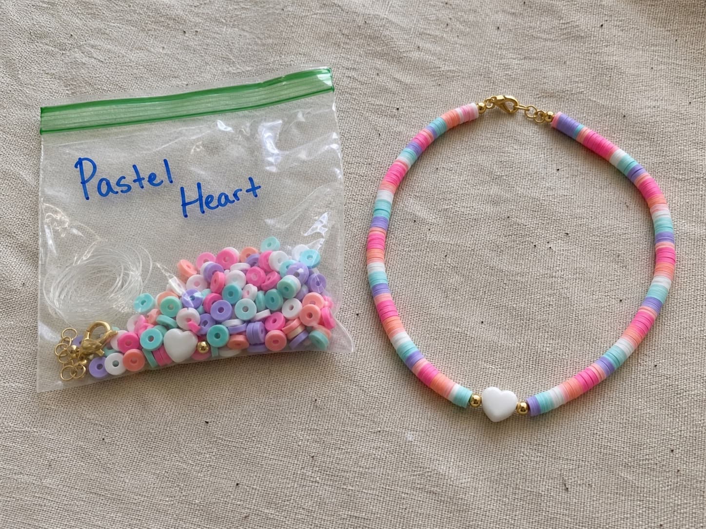 Handmade pastel heart necklace beside its clear DIY bead kit