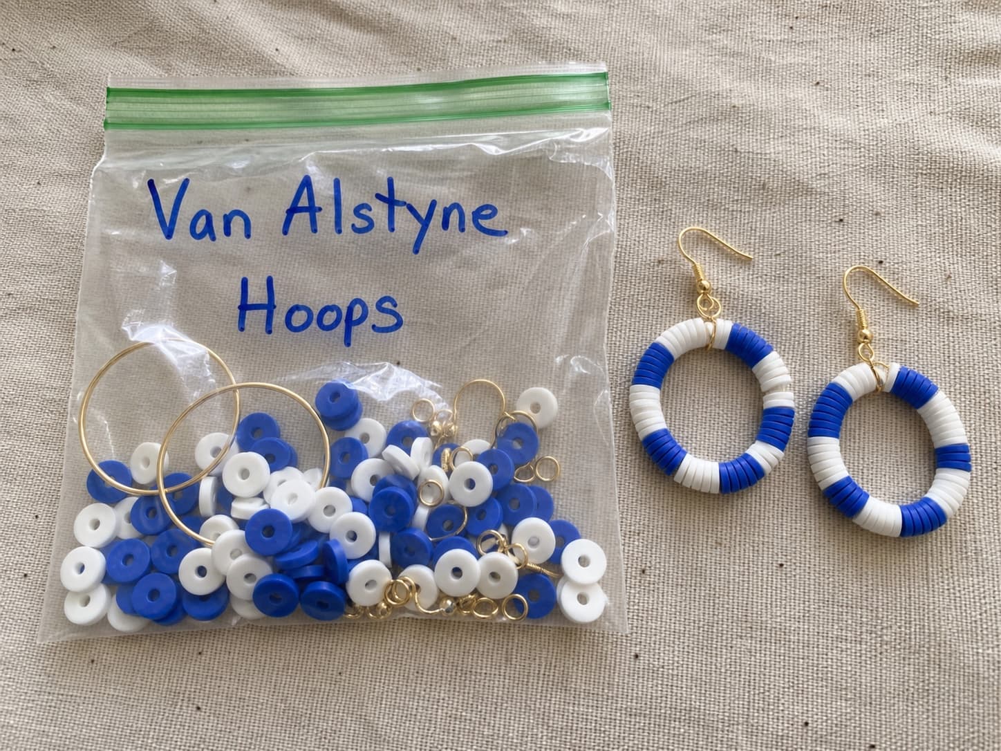Handmade royal blue and white Van Alstyne hoop earrings beside their clear DIY kit